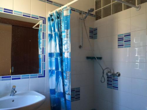 a bathroom with a blue shower curtain and a sink at Horta Grande in Silves