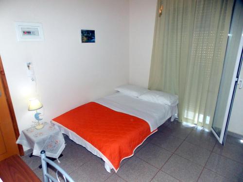 a small bed with an orange blanket in a room at Nikos Apartments in Ormos Panagias