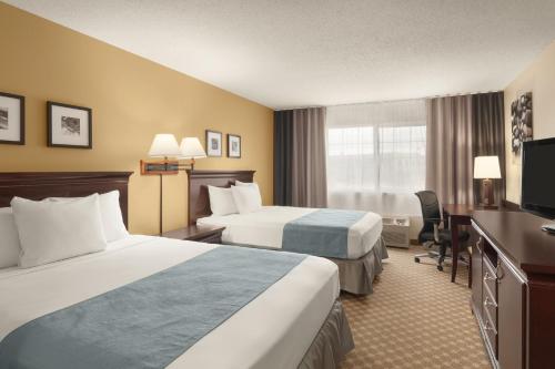 スーフォールズにあるCountry Inn & Suites by Radisson, Sioux Falls, SDのベッド2台とデスクが備わるホテルルームです。