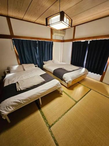 a bedroom with two beds and a window at 博多駅徒歩8分の古民家ホテル in Fukuoka