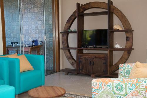 a living room with a tv on a wooden entertainment center at Pousada La Dolce Vita in Búzios