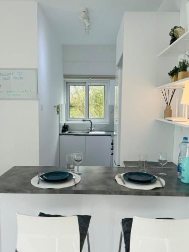 a kitchen with a table with two plates and glasses at White 1-bdr apartment Agyos Tychonas in Limassol