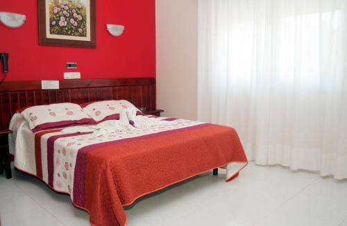 a bedroom with a bed with a red wall at Hotel Ria Toxa in Revolta