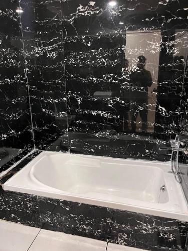 a white bath tub in a black tiled bathroom at HOTEL RK VILLA , Naroda in Ahmedabad