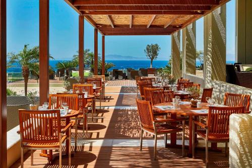 Un restaurante con mesas y sillas de madera en un patio. en Sheraton Rhodes Resort, en Ixia