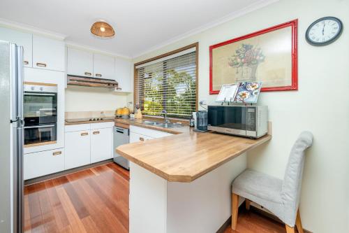 a kitchen with white cabinets and a wooden counter top at Narrow Neck Retreat in Katoomba