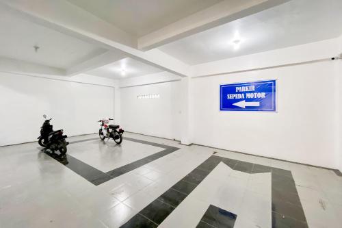 two motorcycles parked in a white room with a sign on the wall at Urbanview Hotel Pelita Inn Medan in Pulauberayan Dadap