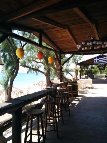 a bar with stools and tables and a view of the beach at Apartments Katoji in Chrani
