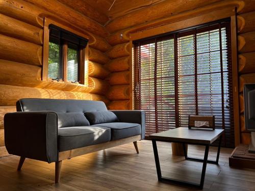 a living room with a couch and a table at Prime勝沼 森の中のプライベートログハウス 緑に包まれてBBQを楽しむ癒しの空間 in Koshu