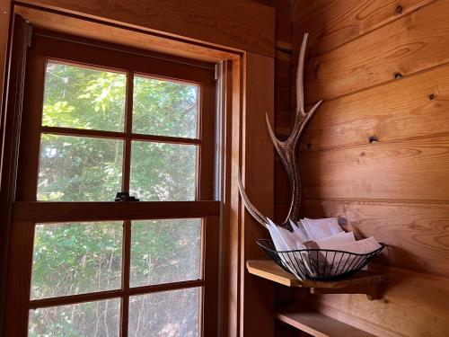 a basket on a shelf next to a window at Prime勝沼 森の中のプライベートログハウス 緑に包まれてBBQを楽しむ癒しの空間 in Koshu