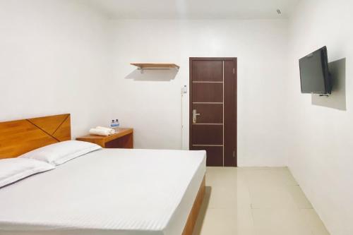 a bedroom with a white bed and a television at Urbanview Hotel Pelita Inn Medan in Pulauberayan Dadap