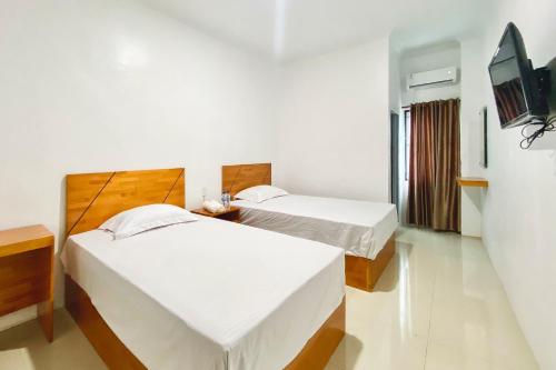 a bedroom with two beds and a tv in it at Urbanview Hotel Pelita Inn Medan in Pulauberayan Dadap