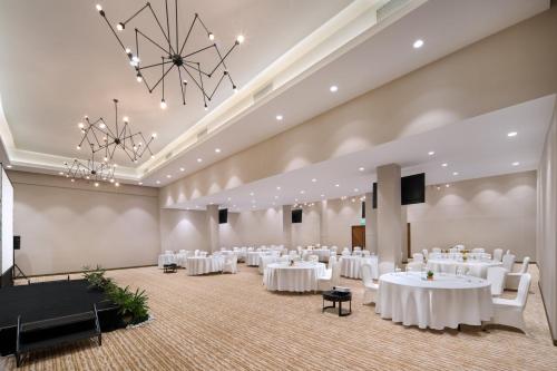 a banquet hall with white tables and chairs and a chandelier at Hilton Garden Inn Bali Ngurah Rai Airport in Kuta