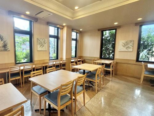 a dining room with tables and chairs and windows at Hotel Route-Inn Kakegawa Inter in Kakegawa