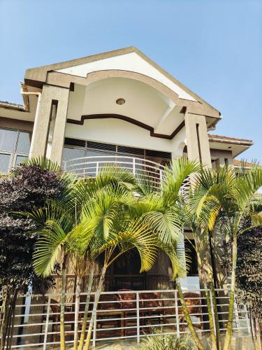 a house with palm trees in front of it at Hidden beautiful Modern Apartment in Entebbe
