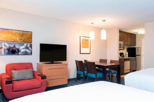 a hotel room with a bed and a dining room at TownePlace Suites Fort Wayne North in Fort Wayne