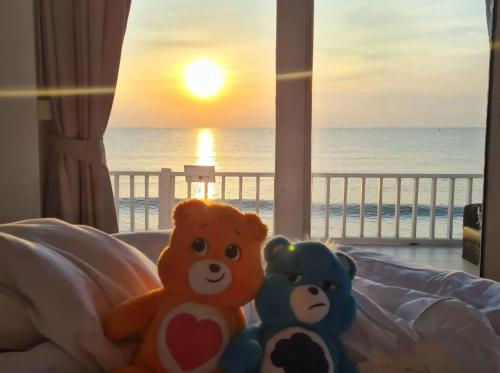 two teddy bears sitting on a bed watching the sunset at THE SKY EXCLUSIVE VILLA Bluesky in Ban Tha Sai