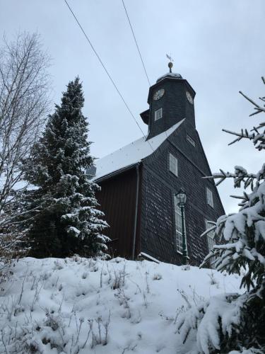 a black barn in the snow with a christmas tree at Hotel & Restaurant Druidenstein in Trautenstein