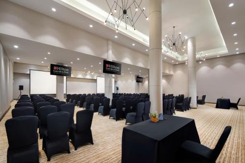 a conference room with black chairs and a screen at Hilton Garden Inn Bali Ngurah Rai Airport in Kuta