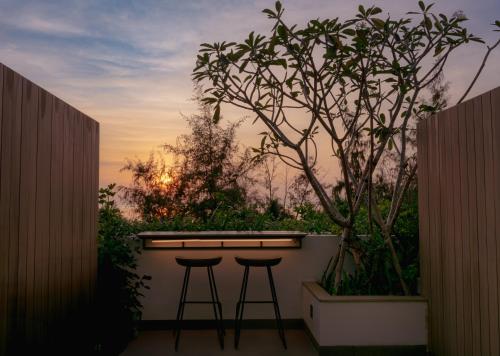 two bar stools sitting on a balcony with a tree at Soul Boutique Hotel Phu Quoc in Phu Quoc