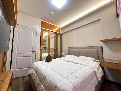 ein Schlafzimmer mit einem großen weißen Bett und einer Tür in der Unterkunft The Cozysweet Homestay in Manila