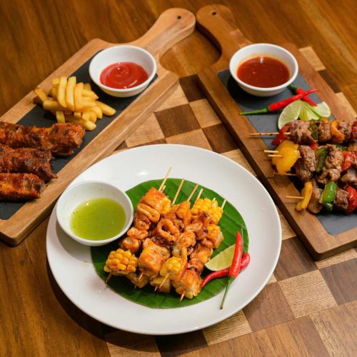a table with a plate of food on a table at Wink Icon Hotel Danang Riverside - 24hrs Stay & Rooftop Pool Bar in Da Nang