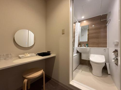 un bagno con un water, un lavandino e uno specchio di 南紀月の瀬温泉ぼたん荘 a Takaike