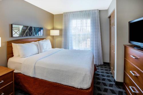 a hotel room with a bed and a television at TownePlace Suites by Marriott Detroit Livonia in Livonia