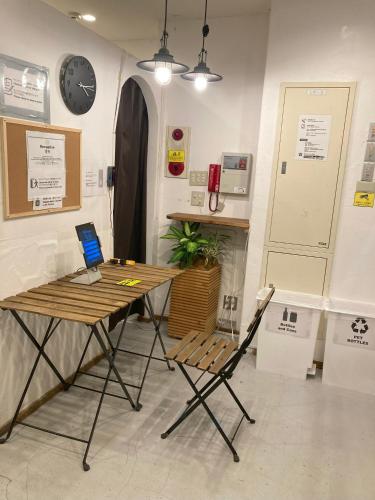 a table and chairs in a room with a clock at Hostel Lodging Tokyo Ueno in Tokyo