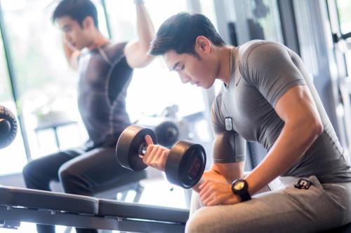 a man holding a dumbbell in a gym at Cross Vibe Bangkok Sukhumvit in Bangkok