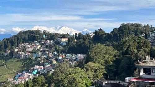 a town on a hill with mountains in the background at Windchimes Homestay in Darjeeling