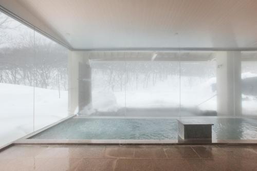 a swimming pool in a room with a glass wall at Hotel Jogakura in Aomori