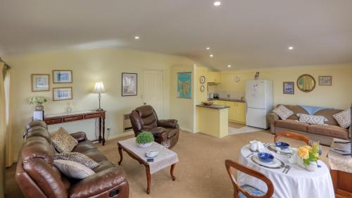 a living room with leather furniture and a kitchen at Birchwood on the River - Devonport, Tasmania - Self-Contained and Self-Catering Accommodation in Devonport