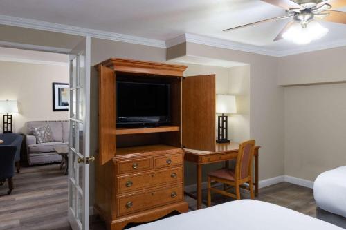 a living room with a television and a desk with a desk at Travelodge by Wyndham Monterey Bay in Monterey