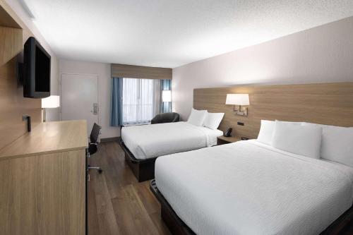 a hotel room with two beds and a television at Baymont by Wyndham Nashville Airport in Nashville