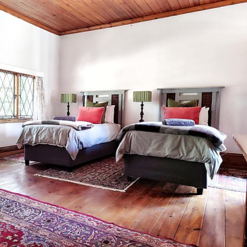 two beds in a bedroom with wooden floors at The Writer's House in Bedford