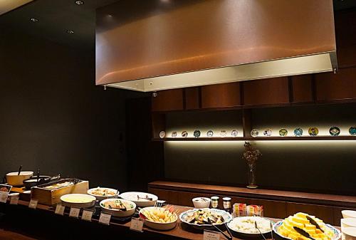 a buffet line with plates of food in a restaurant at HOTEL AMANEK Kanazawa in Kanazawa