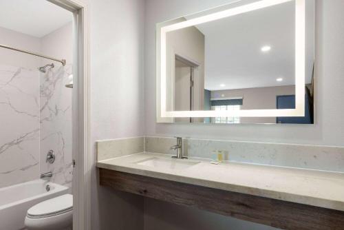 a bathroom with a sink and a mirror and a toilet at Days-Inn by Wyndham Bakersfield in Bakersfield