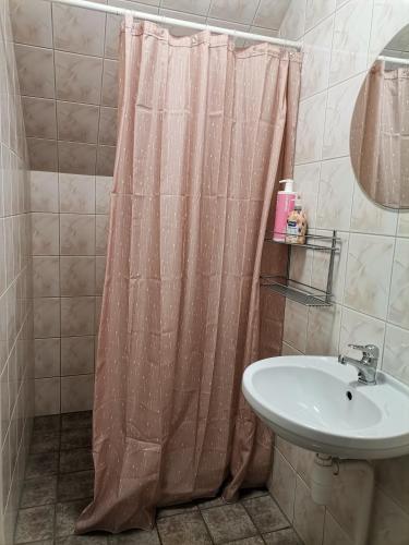 a bathroom with a shower curtain and a sink at Guesthouse Laurits in Kuressaare