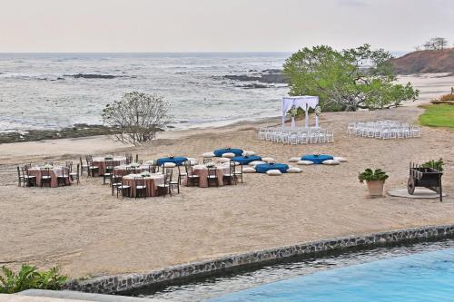 a beach with a bunch of tables and chairs on the sand at JW Marriott Guanacaste Resort & Spa in Tamarindo