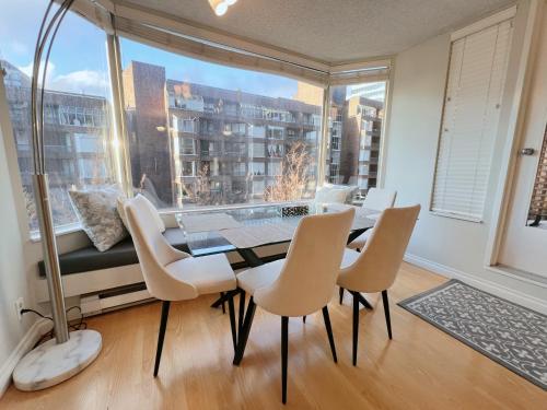 Un comedor con mesa y sillas y una gran ventana. en Beautiful 2 Beds Dwtn apt Free Parking King Bed, en Vancouver