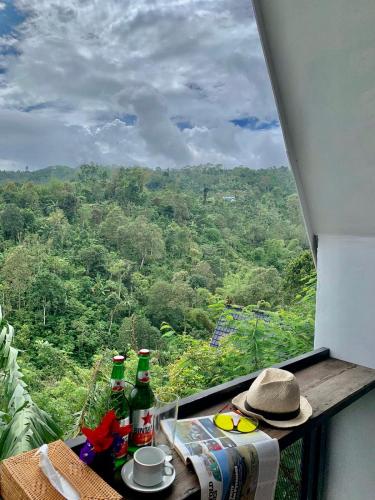 a table with drinks and a hat on a balcony with a view at green slope villa glamping in Gitgit