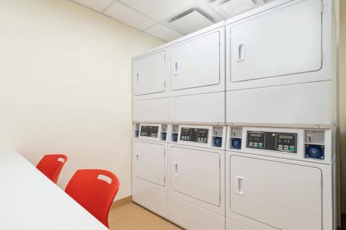 a room with white cabinets and red chairs at TownePlace Suites by Marriott Logan in Logan