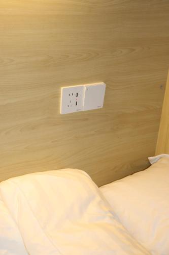 a white switch on a wooden wall next to a bed at The Moment Hostel in Bangkok