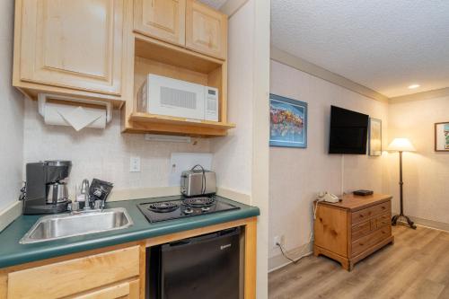 a kitchen with a sink and a microwave at Mountainside Inn 314 by Alpine Lodging Telluride in Telluride