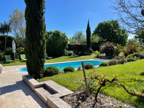 une piscine dans un jardin avec un arbre dans l'établissement Manoir des Rosiers, à Noyant-la-Plaine