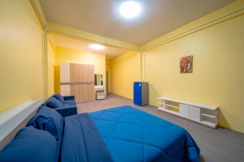 a bedroom with a large blue bed and yellow walls at UrbanNest Hostel in Pattaya