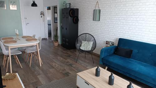 un salon avec un canapé bleu et une table dans l'établissement Charmant appartement proche Thales, à Cholet