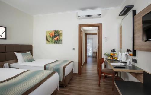 a hotel room with two beds and a desk at Kimeros Park Holiday Village - Ultra All Inc. Kids Concept in Kemer