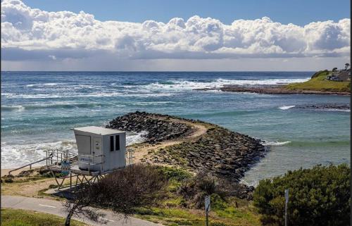 a small building on the shore of the ocean at Salt Life By The Point On Warilla Beach in Barrack Point